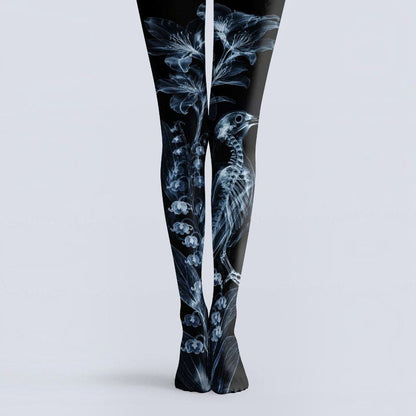 Avaeri black tights are printed with white X-ray-style patterns of flowers and bird skeletons, crafted from comfortable stretch fabric to showcase a dark romantic aesthetic.